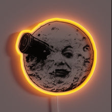 Charger l&#39;image dans la galerie, This neon sign features the iconic image from Georges Méliès’ *A Trip to the Moon* (1902), one of the earliest and most influential films in cinema history. The artwork shows the moon with a human face being struck in the eye by a space capsule — a legendary scene symbolizing early cinematic imagination and the birth of science fiction in film.