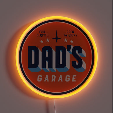 Retro-style neon sign reading “Dad’s Garage” with “Full Service” and “Open 24 Hours” in small text. The circular sign glows with a warm orange neon border.