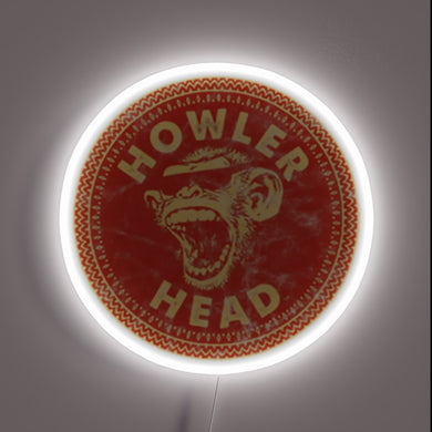 Howler Head Whiskey neon sign with a bold red circular design featuring a roaring monkey and white neon glow outlining the logo.
