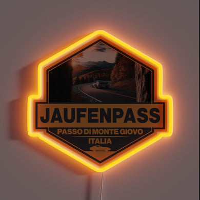 Jaufenpass Italy neon badge with winding road and mountain scene.