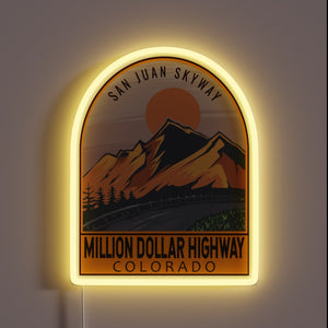 Million Dollar Highway Colorado neon sign with mountain silhouette and glowing arch.
